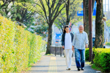 施設周辺の散歩路。緑に囲まれた歩道で入居者と職員が歩いている。